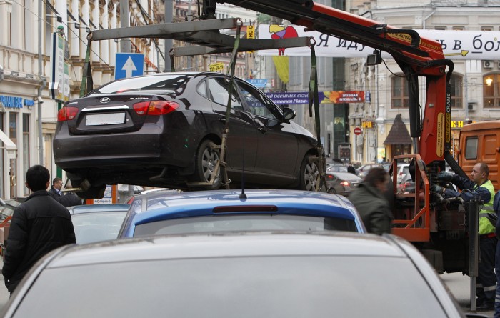 File photo of city authorities lifting a car parked on a pedestrian crossing before towing it away in Moscow